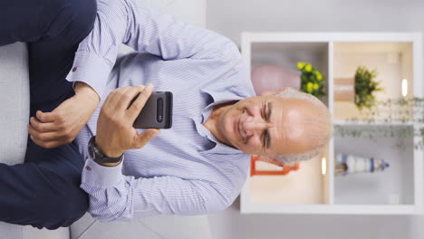 Vertikales-Video-Eines-Alten-Mannes,-Der-Mit-Glücklichem-Gesichtsausdruck-SMS-Am-Telefon-Schreibt.